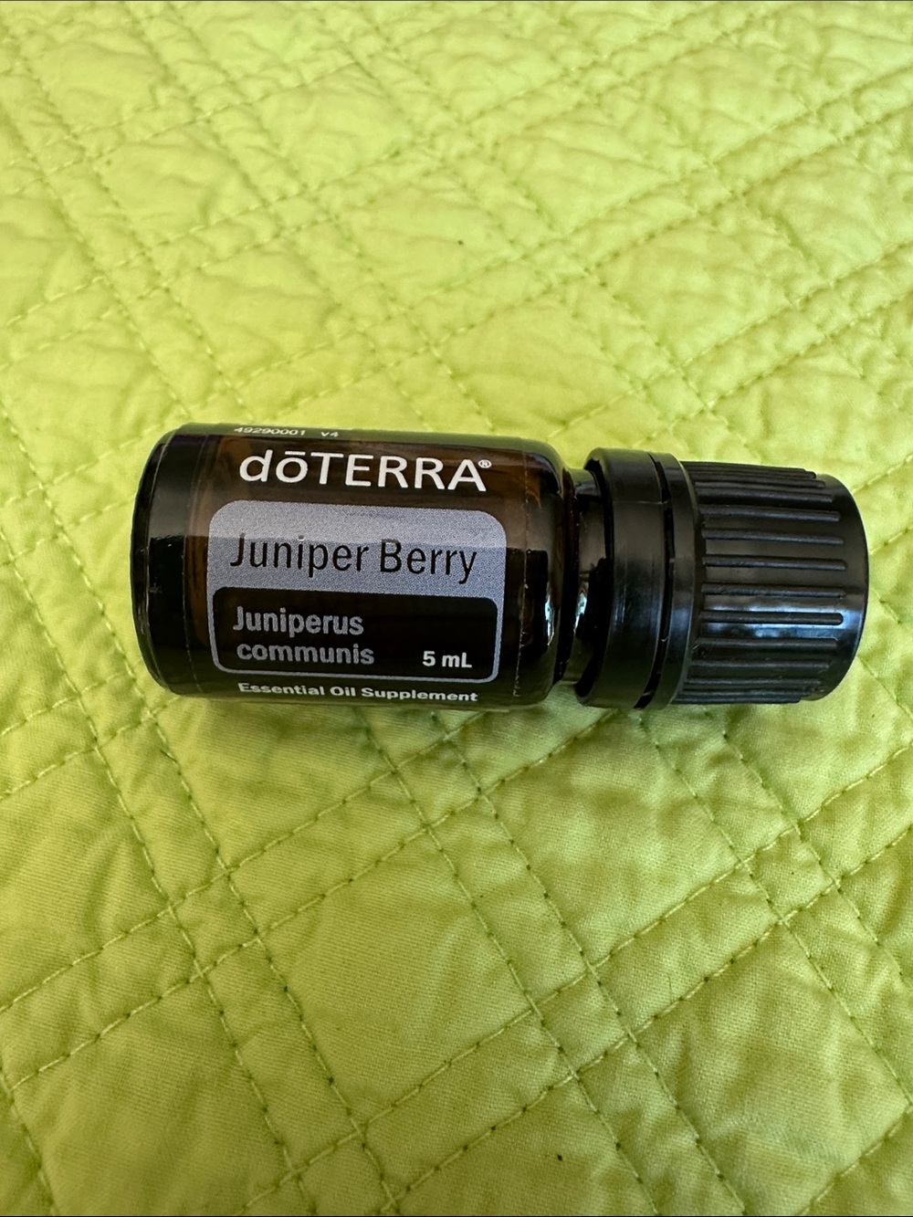 Doterra Juniper Berry Essential Oil Bottle with Black Cap on Lime Green Surface